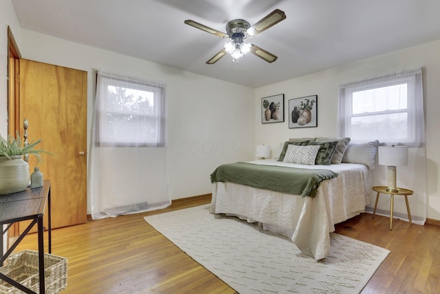 bedroom with hardwood / wood-style flooring, ceiling fan, and multiple windows