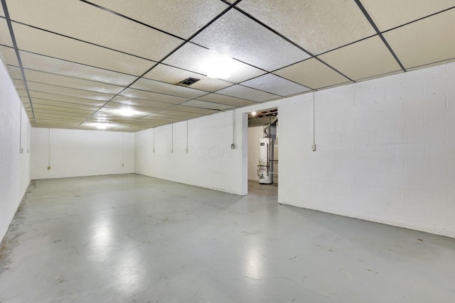 basement featuring a paneled ceiling and water heater