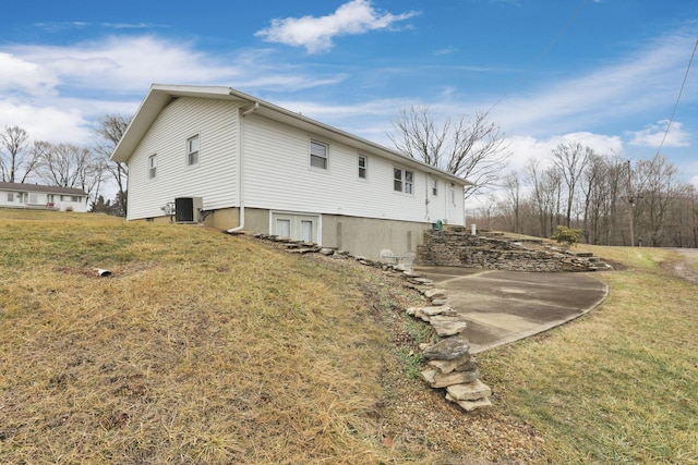 view of side of home featuring central AC unit and a yard