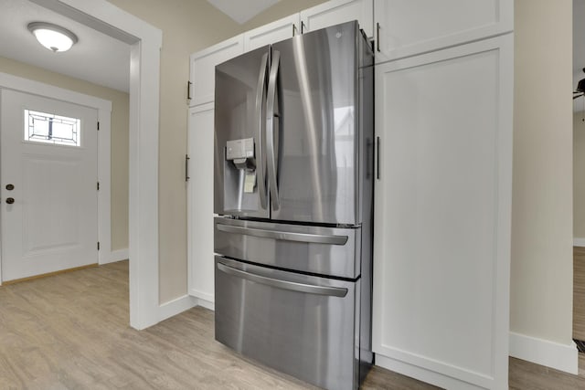 kitchen with light wood-type flooring, white cabinets, and stainless steel refrigerator with ice dispenser