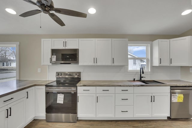 kitchen with white cabinetry, stainless steel appliances, sink, and hardwood / wood-style floors