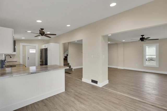 kitchen featuring sink, stainless steel fridge, ceiling fan, light hardwood / wood-style floors, and white cabinets