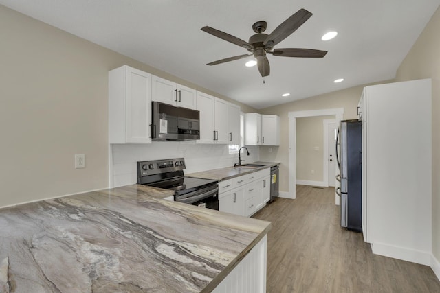 kitchen with appliances with stainless steel finishes, white cabinetry, sink, backsplash, and kitchen peninsula