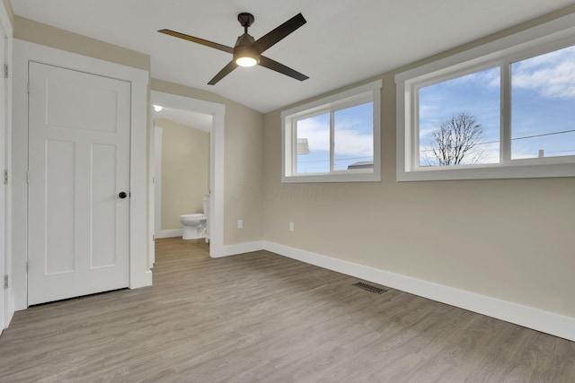 unfurnished bedroom featuring lofted ceiling, ensuite bath, light hardwood / wood-style floors, and ceiling fan