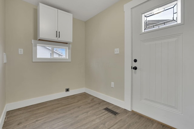 laundry area featuring cabinets, hookup for an electric dryer, and light hardwood / wood-style floors