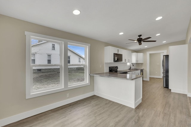 kitchen featuring sink, stainless steel refrigerator, kitchen peninsula, black range with electric stovetop, and white cabinets