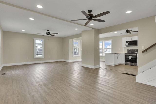 unfurnished living room with ceiling fan, a healthy amount of sunlight, and light hardwood / wood-style flooring