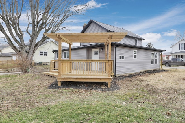 back of property with a wooden deck, a pergola, and a lawn