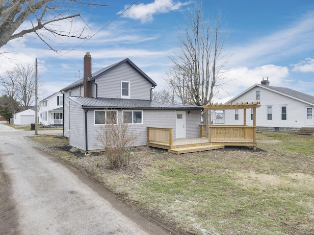 rear view of property featuring a deck and a lawn