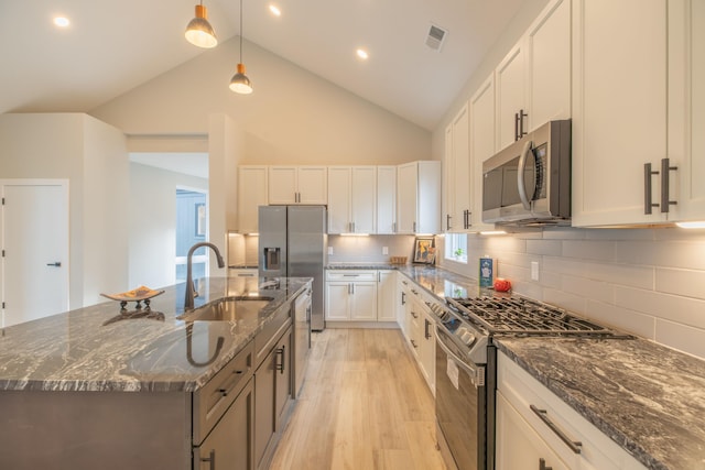 kitchen featuring decorative light fixtures, dark stone counters, white cabinets, and appliances with stainless steel finishes