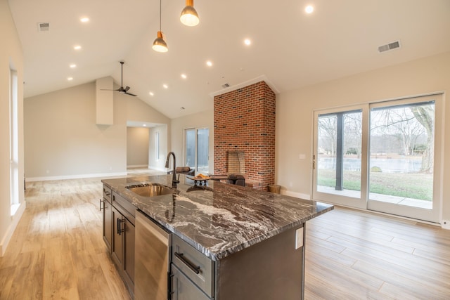 kitchen featuring decorative light fixtures, sink, dark stone countertops, stainless steel dishwasher, and light wood-type flooring