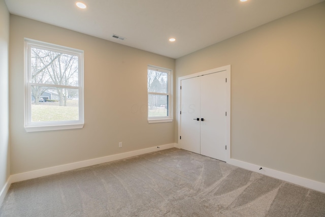 unfurnished bedroom with multiple windows, a closet, and light carpet