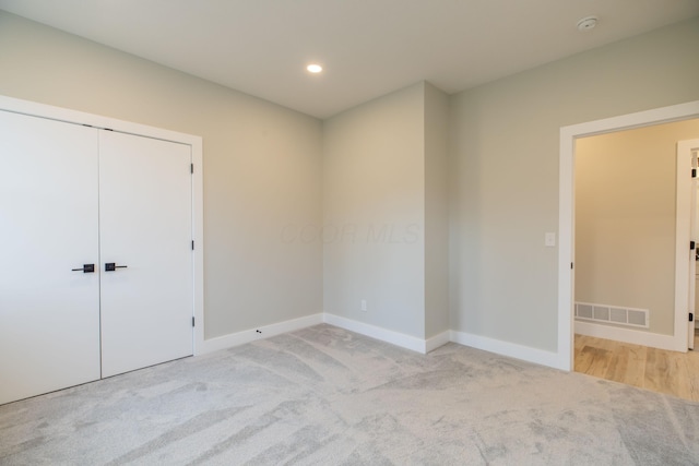 unfurnished bedroom featuring light carpet and a closet