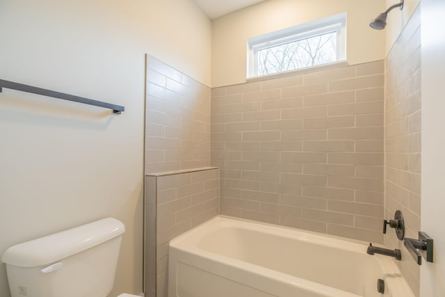 bathroom with tiled shower / bath combo and toilet