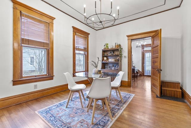 dining space with ornamental molding, a chandelier, and light hardwood / wood-style floors