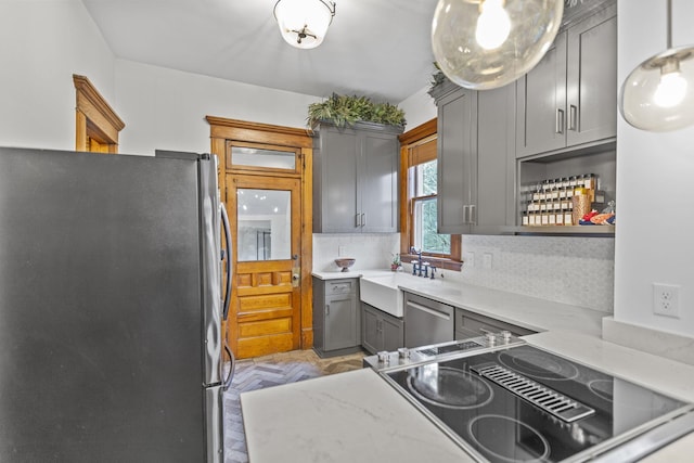 kitchen featuring gray cabinetry, tasteful backsplash, pendant lighting, stainless steel appliances, and light parquet floors