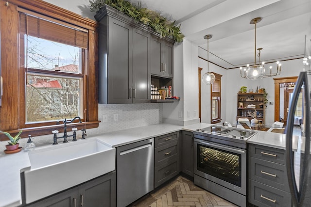 kitchen featuring pendant lighting, sink, appliances with stainless steel finishes, backsplash, and dark parquet flooring