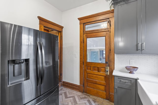 kitchen featuring gray cabinets, sink, stainless steel fridge, and decorative backsplash