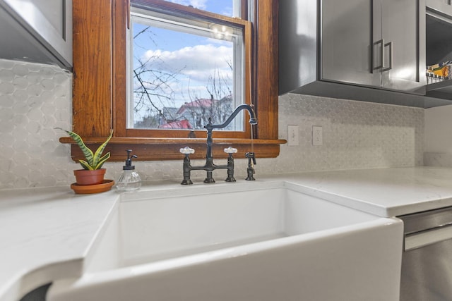 room details featuring tasteful backsplash, sink, light stone counters, and stainless steel dishwasher