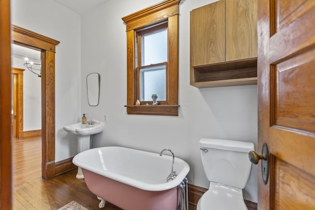 bathroom with a washtub, hardwood / wood-style flooring, and toilet