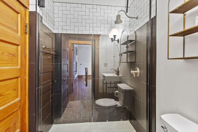 bathroom with tile walls, sink, a shower with door, and toilet