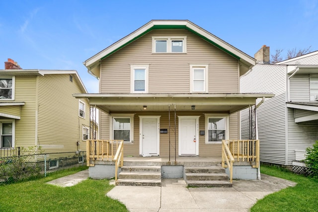 traditional style home featuring a porch, a front lawn, and fence