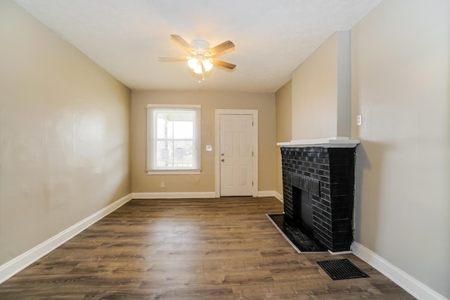 unfurnished living room featuring a fireplace, visible vents, a ceiling fan, baseboards, and dark wood finished floors