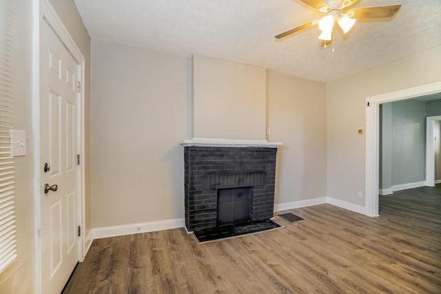 unfurnished living room featuring a fireplace, wood finished floors, a ceiling fan, and baseboards