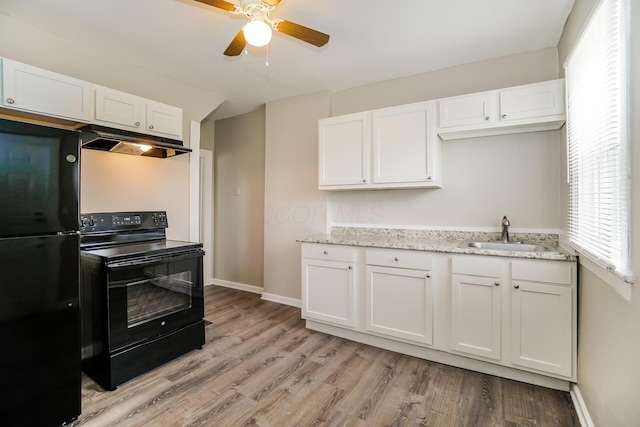 kitchen with black appliances, a sink, white cabinetry, and under cabinet range hood