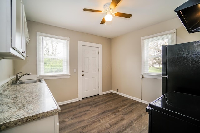 kitchen featuring light countertops, dark wood-type flooring, white cabinetry, a sink, and black appliances