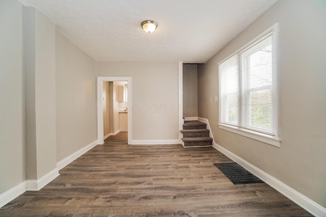 spare room featuring baseboards, stairs, visible vents, and wood finished floors