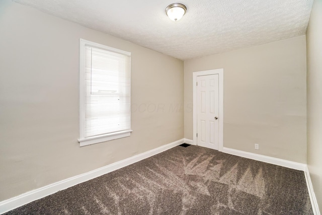 carpeted spare room featuring a textured ceiling and baseboards