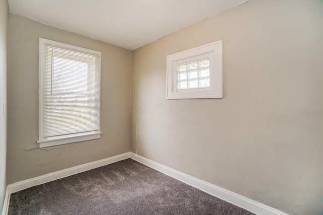 empty room with baseboards and dark carpet