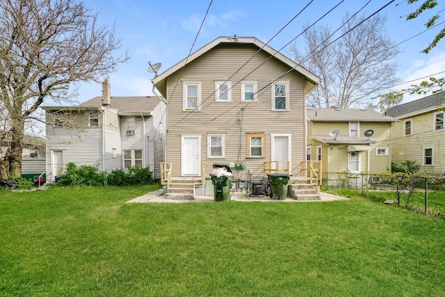 rear view of property with entry steps, a lawn, and fence