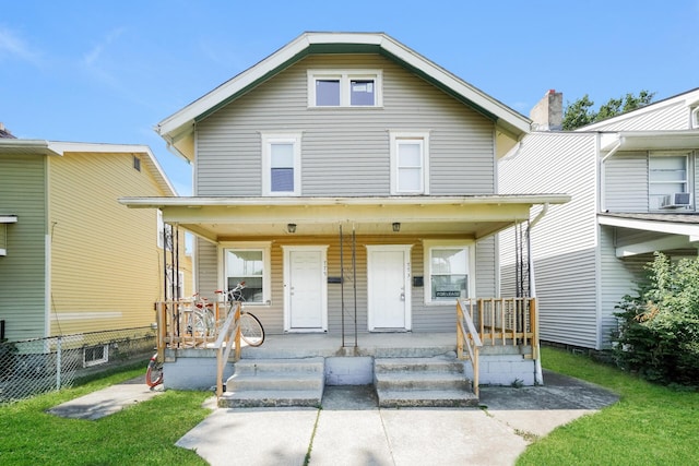 american foursquare style home with covered porch, fence, and a front lawn