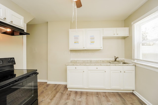 kitchen featuring electric range, a sink, light wood-style floors, and under cabinet range hood