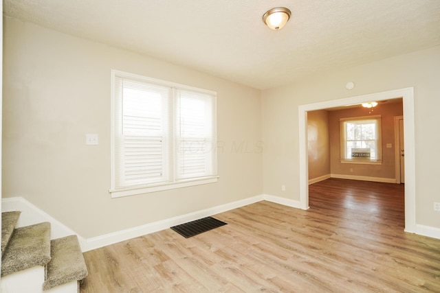 interior space with baseboards, visible vents, stairway, wood finished floors, and a textured ceiling