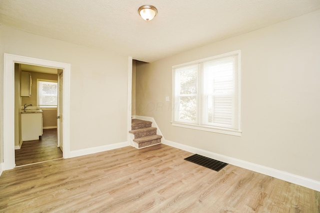 unfurnished room featuring baseboards, visible vents, and light wood finished floors