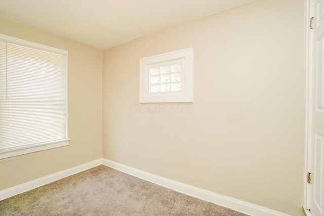 carpeted spare room featuring baseboards