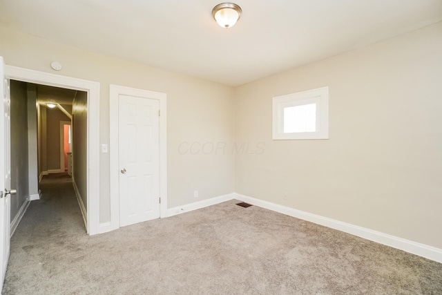 unfurnished room with carpet flooring and baseboards