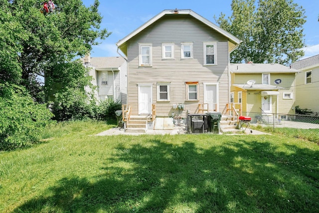 rear view of house featuring entry steps, a lawn, and fence