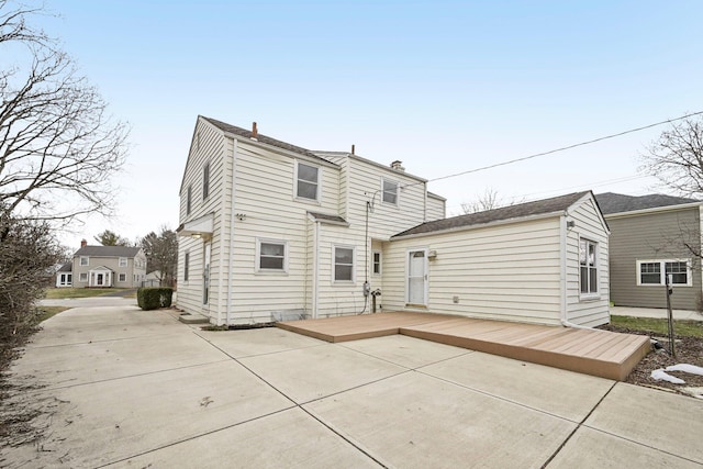 rear view of property featuring a wooden deck and a patio