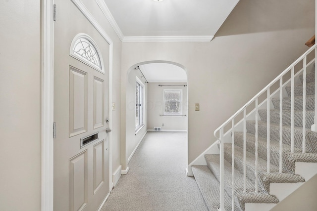 carpeted foyer entrance featuring crown molding