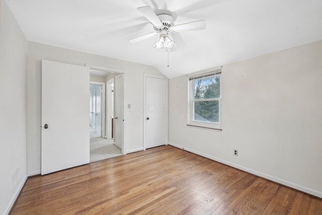 spare room with ceiling fan, lofted ceiling, and light wood-type flooring