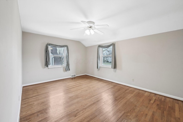 empty room featuring hardwood / wood-style flooring, vaulted ceiling, and ceiling fan