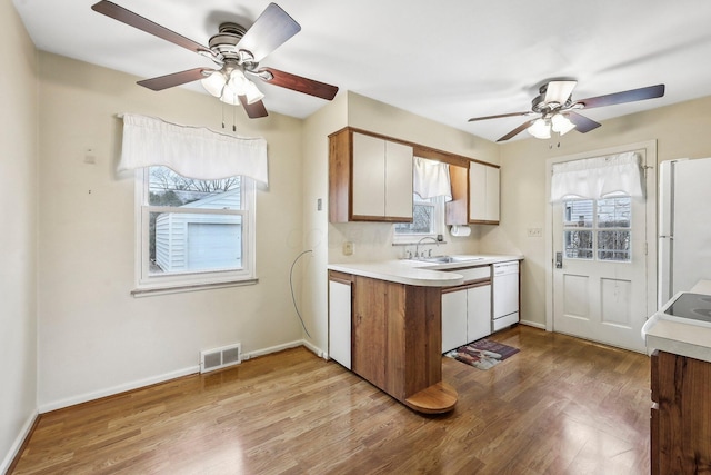 kitchen with white cabinetry, sink, light wood-type flooring, ceiling fan, and white appliances