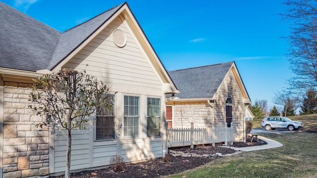 view of property exterior featuring stone siding and a shingled roof