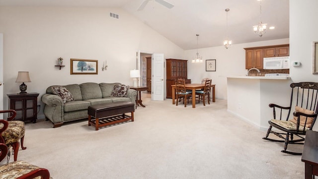 living room with ceiling fan with notable chandelier, light colored carpet, visible vents, and high vaulted ceiling