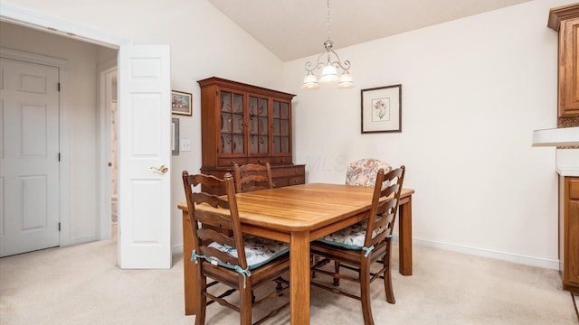 dining area with baseboards, light carpet, a notable chandelier, and vaulted ceiling