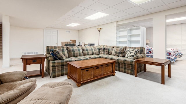 living area featuring a drop ceiling, visible vents, and light colored carpet